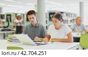 Young male librarian explaining information for casual female while she is using laptop in the library. Стоковое видео, видеограф Яков Филимонов / Фотобанк Лори