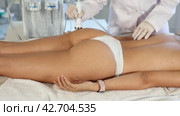 Young woman undergoing machine-based procedure on buttocks using high-frequency ultrasound attachment in cosmetic clinic. Modern hardware cosmetology. Стоковое видео, видеограф Яков Филимонов / Фотобанк Лори