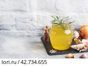 Homemade beef bone and vegetable broth with turmeric seasoning in a glass jar for storage and carrying. Healthy food with collagen and amino acids. Copy space. Стоковое фото, фотограф Глущенко Елена / Фотобанк Лори