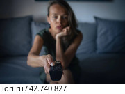 Pretty, young woman sitting on the sofa indoors at home and watc. Стоковое фото, фотограф Viktor Cap / PantherMedia / Фотобанк Лори