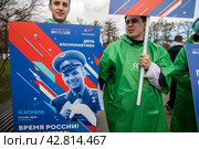 Участники космического шествия держат плакат с портретом Юрия Гагарина в день космонавтики 12 апреля на ВДНХ в городе Москве, Россия (2024 год). Редакционное фото, фотограф Николай Винокуров / Фотобанк Лори