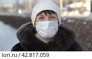 Portrait of middle aged woman in a protective mask with a sad look at camera on outdoors on a frosty winter day in a mink fur coat. Quarantine coronavirus covid-19. Стоковое видео, видеограф EStarodubov / Фотобанк Лори