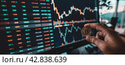 The manager's hand holds a bitcoin coin against a backdrop of futuristic and holographic financial charts. Стоковое AI-изображение, AI-художник Ярославский Максим / Фотобанк Лори