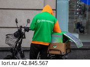Курьер сервиса доставки продуктов Сбермаркет доставляет заказ в центре города Москвы, Россия (2024 год). Редакционное фото, фотограф Николай Винокуров / Фотобанк Лори