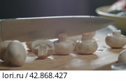 Cook cuts several champignons in half on the kitchen board at once. Стоковое видео, видеограф Strunov David / Фотобанк Лори