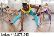 Group of sports multinational people practicing synchronous group choreography in dance studio. Стоковое фото, фотограф Яков Филимонов / Фотобанк Лори