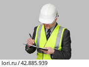 Мужчина в костюме и строительной каске с бумагами в руках делает ревизию. Стоковое фото, фотограф Vladimir Vikhrov / Фотобанк Лори