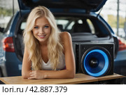 A beautiful blonde girl at an auto sound competition. Car music. Subwoofers, amplifiers, acoustics. Car audio system. Стоковое AI-изображение, AI-художник Александр Поташев / Фотобанк Лори