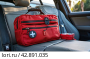 A red first aid kit is in the back seat of a vehicle. Стоковое AI-изображение, AI-художник Юрий Поздников / Фотобанк Лори
