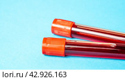 Two tubes with blood on blue background. Person's blood is collected in two tubes for testing for pathological abnormalities in blood test. Concept of medicine, blood test, pathology. Стоковое фото, фотограф Скрипачев Антон / Фотобанк Лори