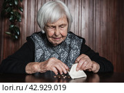 Portrait of an old woman counting money. The concept of old age, poverty, austerity. Стоковое фото, фотограф Matej Kastelic / Фотобанк Лори