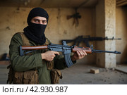 Terrorists with a machine gun on the background of military operations.Isis is a terrorist. Стоковое AI-изображение, AI-художник Александр Поташев / Фотобанк Лори