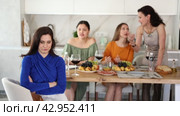 Displeased miffed young brunette sitting arms folded at house get-together, with female friends in background rebuking her, expressing dissatisfaction and disapproval. Стоковое видео, видеограф Яков Филимонов / Фотобанк Лори