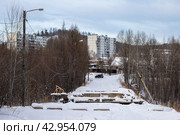 Вид на заснеженную дорогу и обрушившийся мост. Вдали жилые дома. Город Тында, Амурская область, Россия. (2024 год). Стоковое фото, фотограф Андрей Степанов / Фотобанк Лори