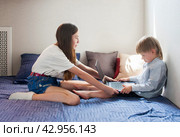 Two children, a boy and a girl, are fighting over a laptop at home. Sibling relationships and technological addiction. Стоковое фото, фотограф Александр Довянский / Фотобанк Лори