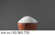 White table salt granules falling into a pile. Wood bowl. Gray color studio background. Condiment particles dropping. Clean cosmetic bath salt pouring footage. Closeup of grained sea salt pieces hill. Стоковое видео, видеограф Марина Демидюк / Фотобанк Лори