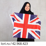 smiling Muslim woman in traditional black hijab holds flag of Great Britain. Стоковое фото, фотограф Яков Филимонов / Фотобанк Лори
