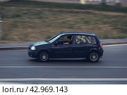 Old car Renault Clio 2 in motion. Young driver is distracted by his phone while driving a car. Редакционное фото, фотограф Константин Григорьев / Фотобанк Лори