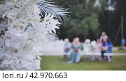 Wedding arch flowers in the background of the guests waiting for the wedding registration in nature. Стоковое видео, видеограф Mikhail Davidovich / Фотобанк Лори