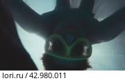 Male figure appearing through streaming sun light underwater to look into camera and rotate. Man having fun diving in swimming pool with mask and taking action camera. Стоковое видео, видеограф Валенти Финаев / Фотобанк Лори