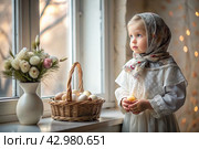 Happy bright Easter. Christianity. Portrait of a three-year-old girl in a Russian folk dress and shawl with a wicker basket with Easter eggs in her hands against the background of an Orthodox church. Стоковое AI-изображение, AI-художник Photojuli / Фотобанк Лори