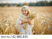 Russian Russian girl in a white dress and a Russian shawl holds golden ears of wheat against the background of a ripening field. The concept of planting and harvesting a rich harvest. Rural landscape. Стоковое AI-изображение, AI-художник Photojuli / Фотобанк Лори