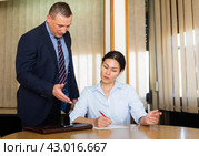 Businessman inviting female business partner to sign papers. Стоковое фото, фотограф Яков Филимонов / Фотобанк Лори