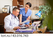 Two focused physicians working with case histories on laptop. Стоковое фото, фотограф Яков Филимонов / Фотобанк Лори