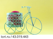 Easter holiday concept - painted red eggs in a stand in the form of a bicycle on a yellow background. Стоковое фото, фотограф Мария Чижик / Фотобанк Лори