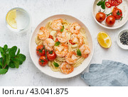 Pasta bavette with fried shrimps, bechamel sauce, mint leaf, garlic, on white plate, top view. Стоковое фото, фотограф Natalia Gdovskaia / Фотобанк Лори