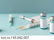 Syringe and glass vial on blue background table. Medical Vials group, needles, ampoules, bottle with medicines or vaccine. Disease treatment. Creative Banner. Anti-aging beauty injections. Vaccination. Стоковое AI-изображение, AI-художник Марина Демидюк / Фотобанк Лори