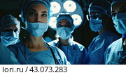 Doctors in operating clothes stand in a semicircle above the operating table in the light of the lighting. Стоковое AI-изображение, AI-художник Ярославский Максим / Фотобанк Лори