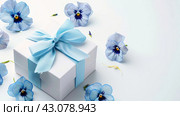 Elegant White Gift Box with Blue Ribbon and Pansies on a Light Background, ai-generated item. Стоковое AI-изображение, AI-художник Юлия Паутова / Фотобанк Лори