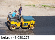 ANGARSK, IRKUTSK REGION, RUSSIA - July 25, 2023: Road workers install an artificial obstacle or speed bump on asphalt roadway. Road roller compacts asphalt over speed bump. View from above. Редакционное фото, фотограф Виктория Катьянова / Фотобанк Лори