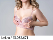 Blonde woman in pink push up bra on gray background, decollete area care. Стоковое фото, фотограф Станислав Тарко / Фотобанк Лори