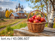 The concept of the Russian Orthodox holiday yablochny spas. A beautiful wicker basket made of vines with red ripe apples on the background of an Orthodox church. Стоковое AI-изображение, AI-художник Photojuli / Фотобанк Лори