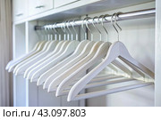 Close-up of white hangers on a white closet. The concept of order and storage in the house. Стоковое AI-изображение, AI-художник Photojuli / Фотобанк Лори