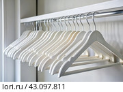 Close-up of white hangers on a white closet. The concept of order and storage in the house. Стоковое AI-изображение, AI-художник Photojuli / Фотобанк Лори