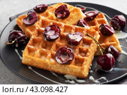 Belgian fluted waffles with fresh cherries and cream on a plate. Soft homemade waffles, sweet dessert with cherries. Стоковое фото, фотограф Глущенко Елена / Фотобанк Лори