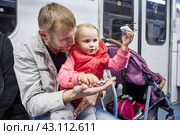 Little girl plays with toy helicopter while traveling inside subway train carriage. Стоковое фото, фотограф Владимир Григорьев / Фотобанк Лори