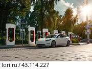 Припаркованный электромобиль под заряжается на электрической зарядной станции. Стоковое AI-изображение, AI-художник Максим Коломыченко / Фотобанк Лори