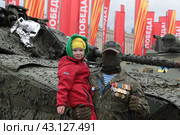 Москва, военный в орденах с девочкой на руках позирует фотографу на выставке военной техники, подбитой во время проведения СВО на Украине (2024 год). Редакционное фото, фотограф Дмитрий Неумоин / Фотобанк Лори