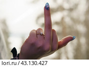 Human hand with agressive  impolite gesture. Teenager gesturing in the spring day outdoors. Sign language. Non-verbal rude communication. Blurred nature as background, Close up image. Стоковое фото, фотограф YuryKara / Фотобанк Лори
