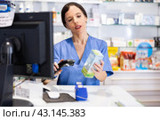 Female pharmacist scans the barcode of product at the checkout in pharmacy. Стоковое фото, фотограф Яков Филимонов / Фотобанк Лори