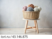 Balls of yarn in a wicker basket in white and beige tones. Needlework, textiles, knitting. Winter season, small business, handmade clothes. Стоковое AI-изображение, AI-художник Photojuli / Фотобанк Лори