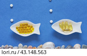 Video of nutrition additions and dietary supplements with fish oil, vitamin E and omega acids. Concept of preventing heart disease using fish oil. Top view of gelatin capsules on fish-shaped plates. Flat lay. Стоковое видео, видеограф Виктория Катьянова / Фотобанк Лори
