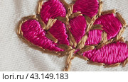 Video of a satin stitch embroidery of a floral ornament with pink flower on a cotton tablecloth. Needlework as a hobby. DIY concept. Top view, macro, flat lay, close-up, mock up. Стоковое видео, видеограф Виктория Катьянова / Фотобанк Лори