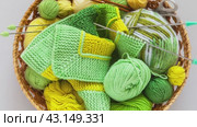 Video of wicker basket with needlework: balls and skeins of green and yellow yarn, knitting needles and striped handmade knitted fabric. DIY concept. Flat lay, top view, close-up, mockup. Стоковое видео, видеограф Виктория Катьянова / Фотобанк Лори
