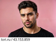 Dissatisfied young man looking unpleasantly away, expresses aversion, smirking at pink background. Guy in black t-shirt scared, negative face expressions concept. Advertising. Copy text space. Стоковое AI-изображение, AI-художник Aleksandr Golubev / Фотобанк Лори