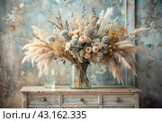 A beautiful bouquet of dried flowers in a glass vase and vials on an antique wooden chest of drawers. A bouquet of flowers in a vase in a home interior. Light, beige, blue floral background. Стоковое AI-изображение, AI-художник Photojuli / Фотобанк Лори